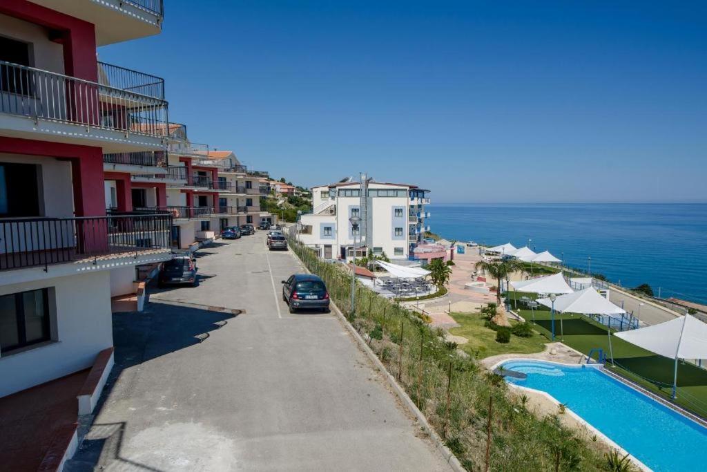 vue d'une rue avec des bâtiments et l'océan dans l'établissement Tus'Hotel, à Castel di Tusa