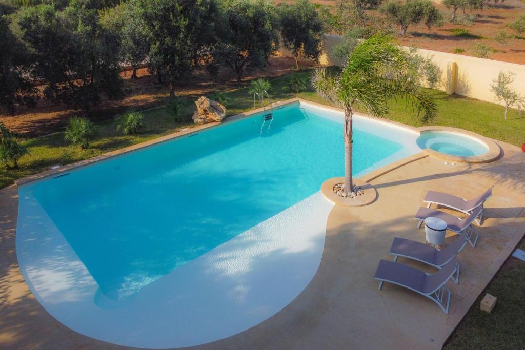 - une vue sur la piscine avec 2 chaises et un palmier dans l'établissement Villa Matilde - Xenia Sicily Villas, à Mazara del Vallo