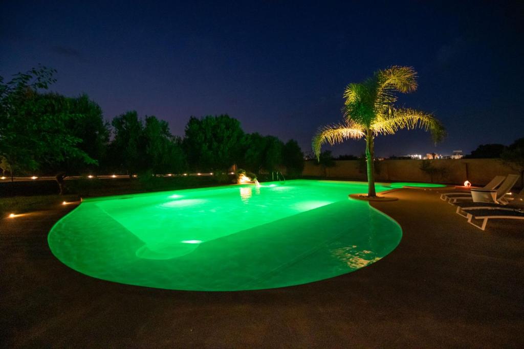 - une piscine verdoyante la nuit avec un palmier dans l'établissement Villa Matilde - Xenia Sicily Villas, à Mazara del Vallo