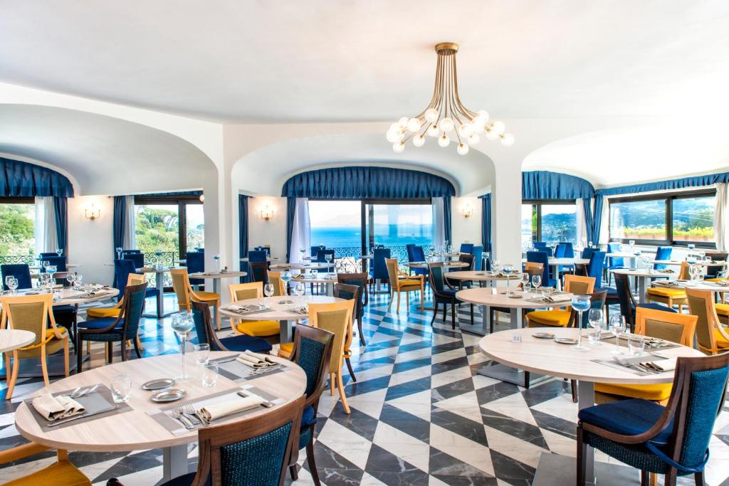un restaurant avec des tables, des chaises et des fenêtres dans l'établissement Hotel San Lorenzo Thermal Spa, à Ischia