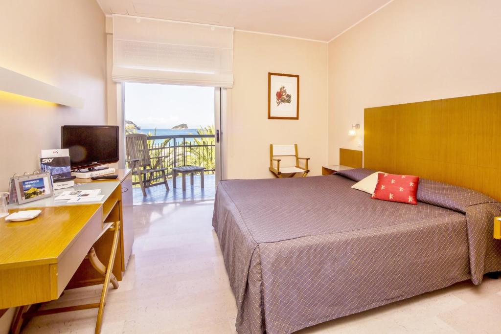 une chambre avec un lit, un bureau et une télévision dans l'établissement Hotel Tirreno, à Spotorno