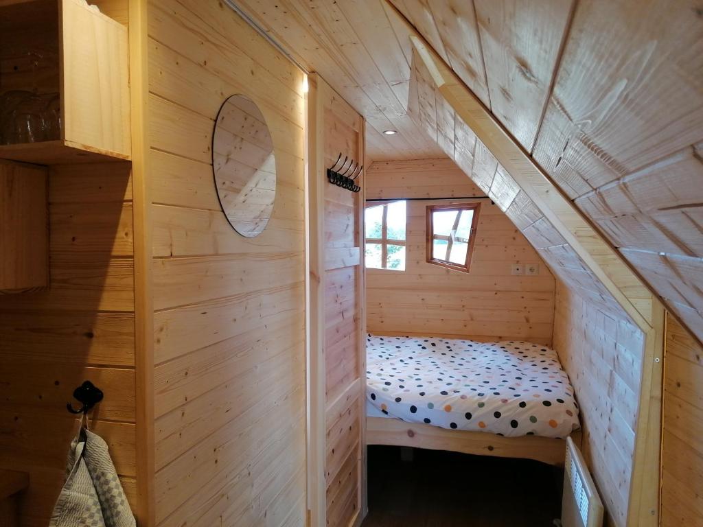 une petite chambre avec un lit dans une cabane en rondins dans l'établissement La Gare de Lurey Conflans gîte et hébergements insolites en Champagne, à Esclavolles-Lurey