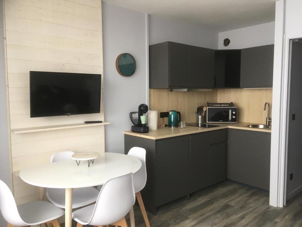 une petite cuisine avec une table et des chaises blanches dans l'établissement Résidence Dome de Polset - Studio 2 adultes et 2 enfants - Wifi, à Val Thorens