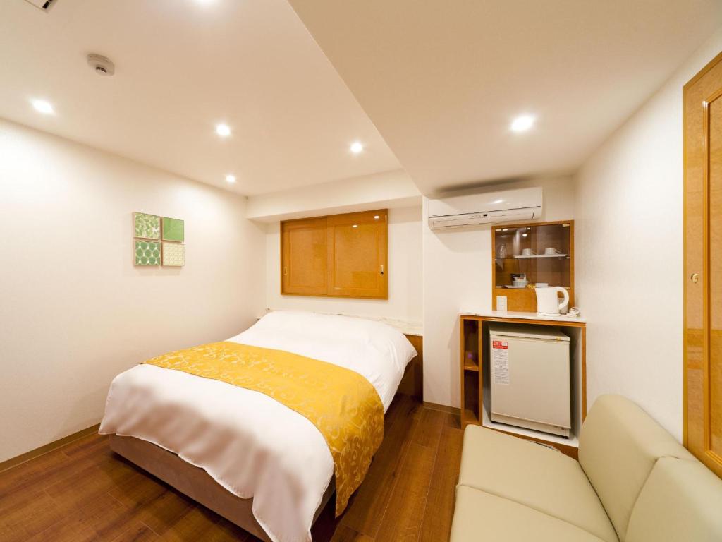 une petite chambre avec un lit et un canapé dans l'établissement Hotel Fine Aroma Tennoji, à Osaka