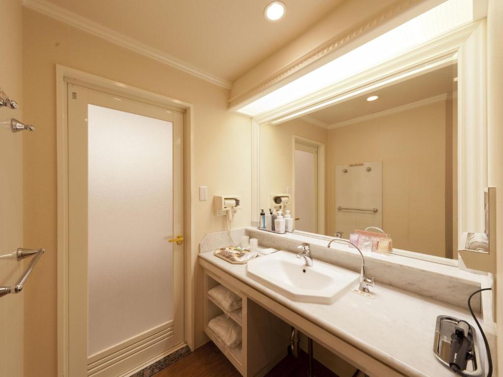 une salle de bain avec un lavabo et un grand miroir dans l'établissement Hotel Fine Aroma Tennoji, à Osaka