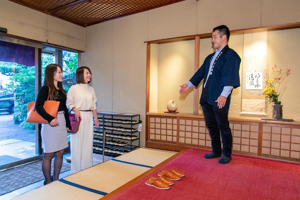 Un homme et deux femmes debout dans une pièce dans l'établissement Atami Onsen Yamaki Ryokan, à Atami