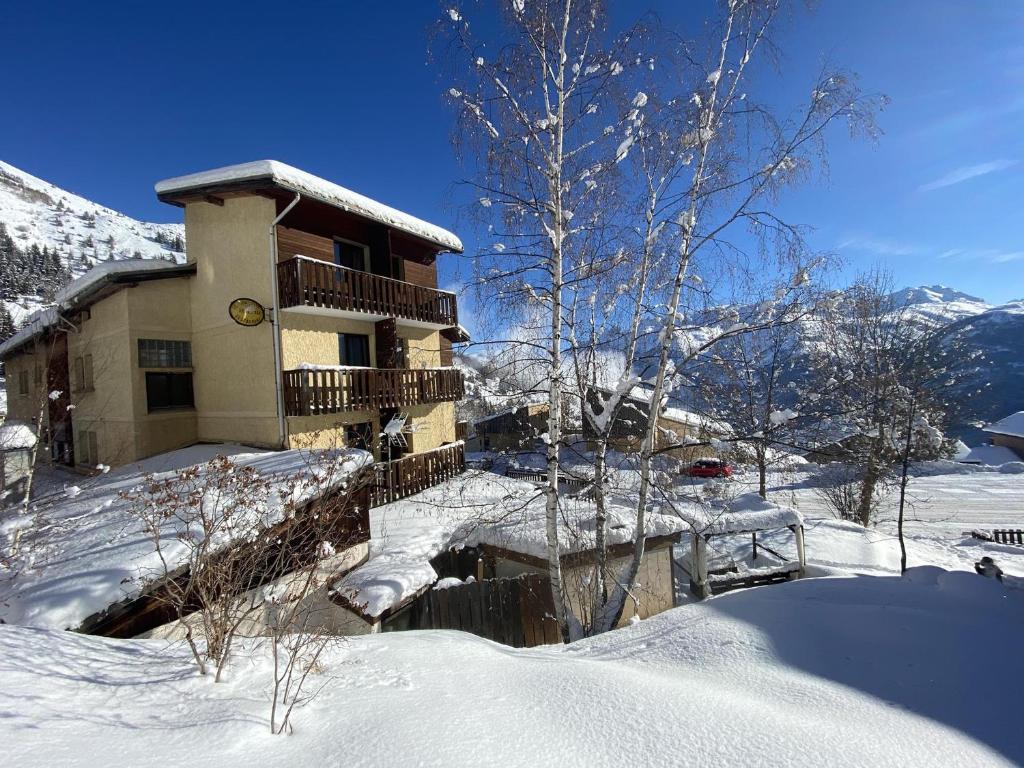 une maison enneigée avec un balcon dans la neige dans l'établissement Hotel Le Beau Site, à Auris