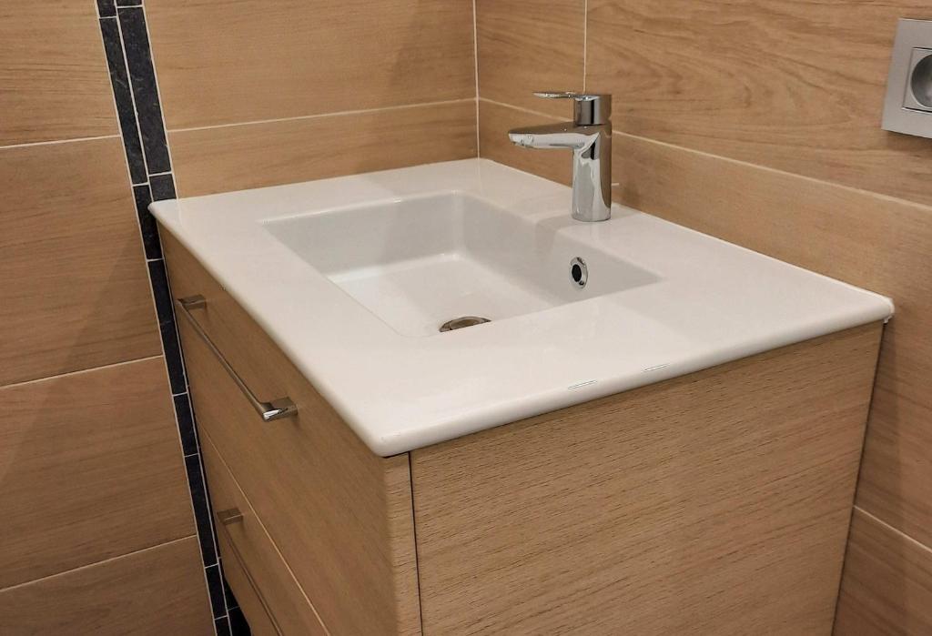 La salle de bains est pourvue d'un lavabo blanc et de murs en bois. dans l'établissement Chalet Monte-Pente, à Megève