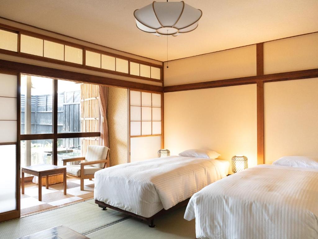 une chambre avec deux lits et une chaise et une fenêtre dans l'établissement HOTEL SHIRAHAMAKAN, à Shirahama 31 autres photos