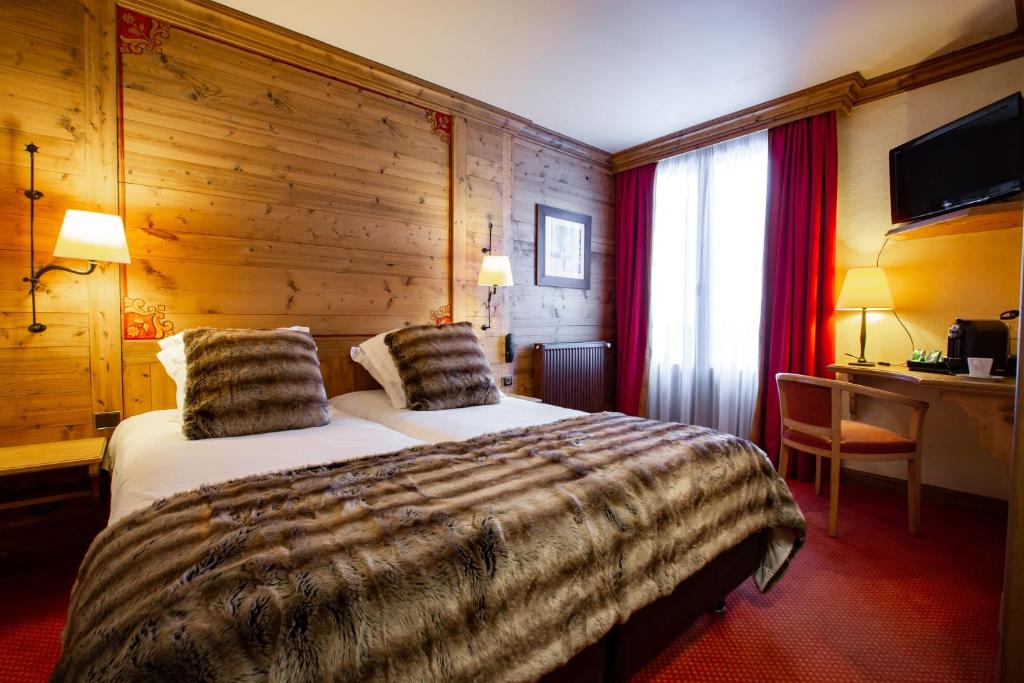 Cette chambre d'hôtel dispose d'un lit avec un mur en bois. dans l'établissement Hôtel Champs Fleuris Morzine, à Morzine