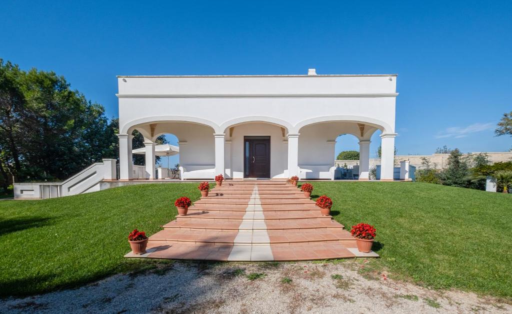 un bâtiment blanc avec un escalier dans l'herbe dans l'établissement Villa Flem Luxury by HDSalento, à Montesano Salentino