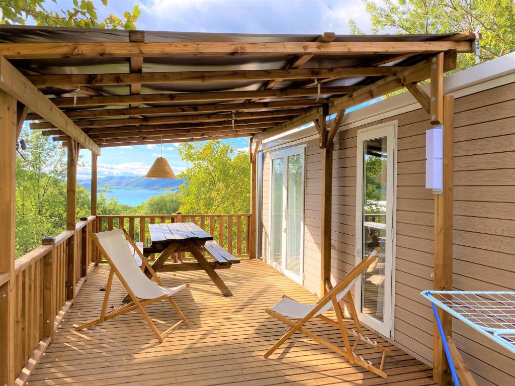 une terrasse en bois avec des chaises et une table de pique-nique. dans l'établissement LES BASTIDES DE CHANTERAINE Bungalows, Lodges & Spa, à Aiguines