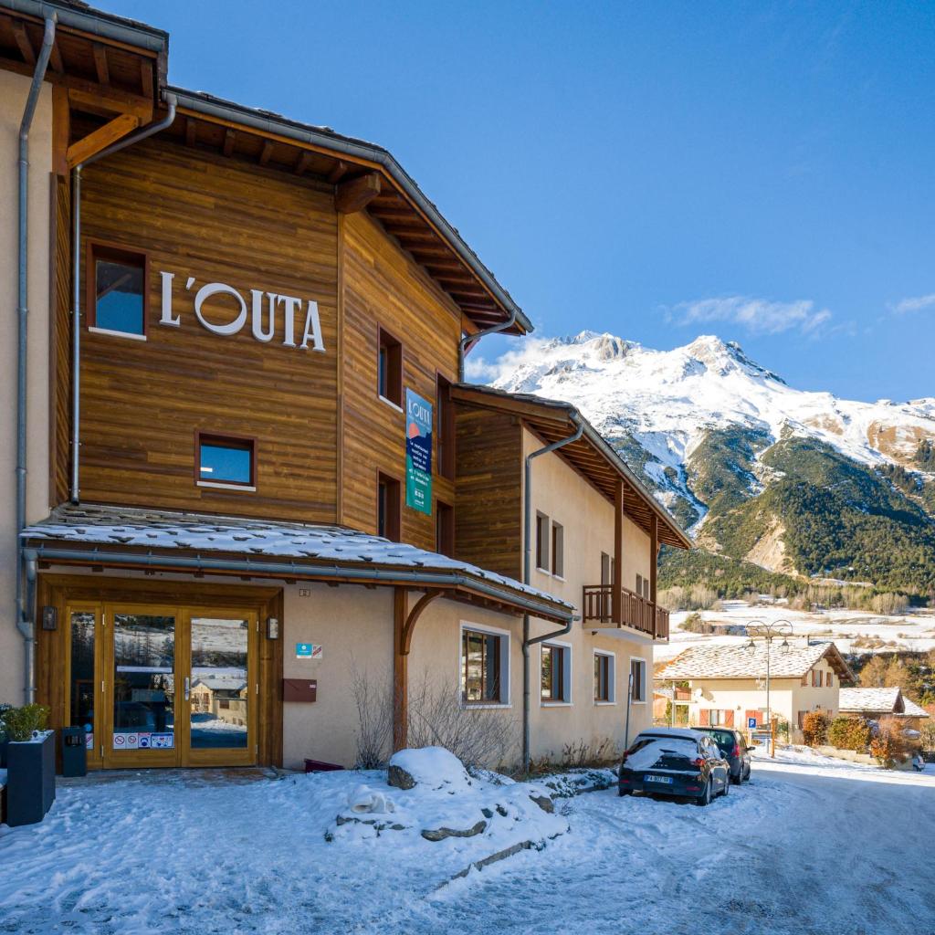 Un bâtiment avec un panneau dans la neige dans l'établissement L'Outa Hotel Restaurant, à Termignon