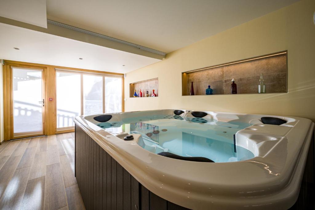 une grande baignoire dans une pièce avec une fenêtre dans l'établissement L'Outa Hotel Restaurant, à Termignon
