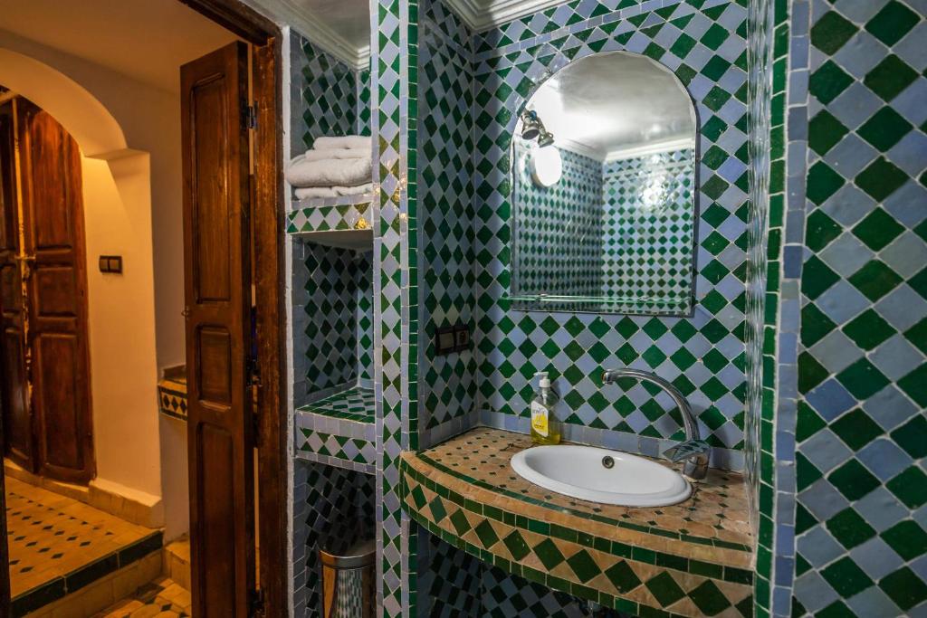 La salle de bains est pourvue d'un lavabo et d'un mur carrelé vert et blanc. dans l'établissement Le Cèdre D'argent, à Fès