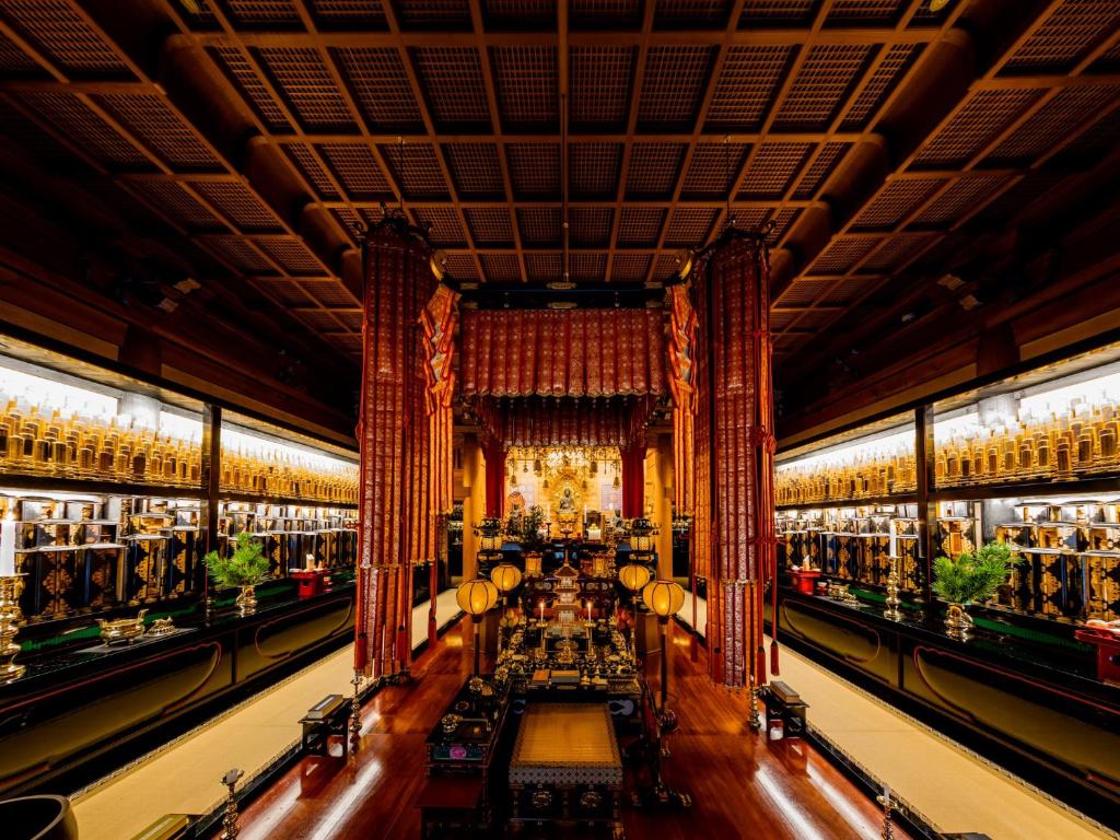 une grande chambre avec des tables et des lustres dans un bâtiment dans l'établissement 高野山 宿坊 恵光院 -Koyasan Syukubo Ekoin Temple-, à Koyasan
