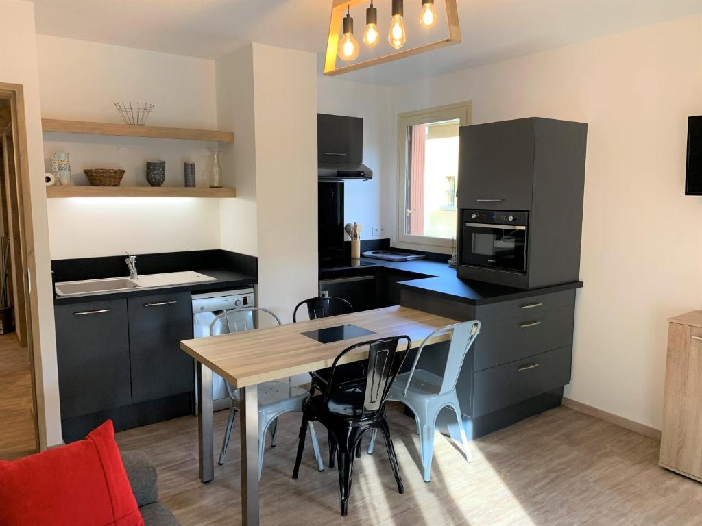 une cuisine avec une table et des chaises dans une pièce dans l'établissement Le cozy du soulan - T2 bis - soda, à Luchon