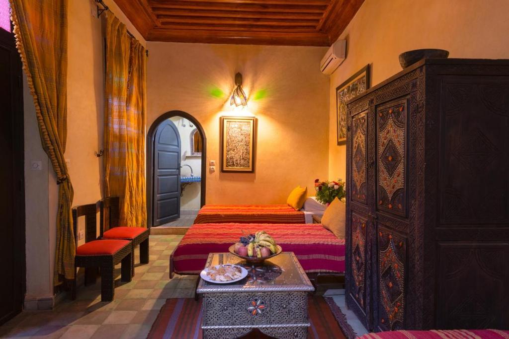 - une chambre avec 2 lits et une table avec un bol de fruits dans l'établissement Riad Lalla Khiti, à Marrakech