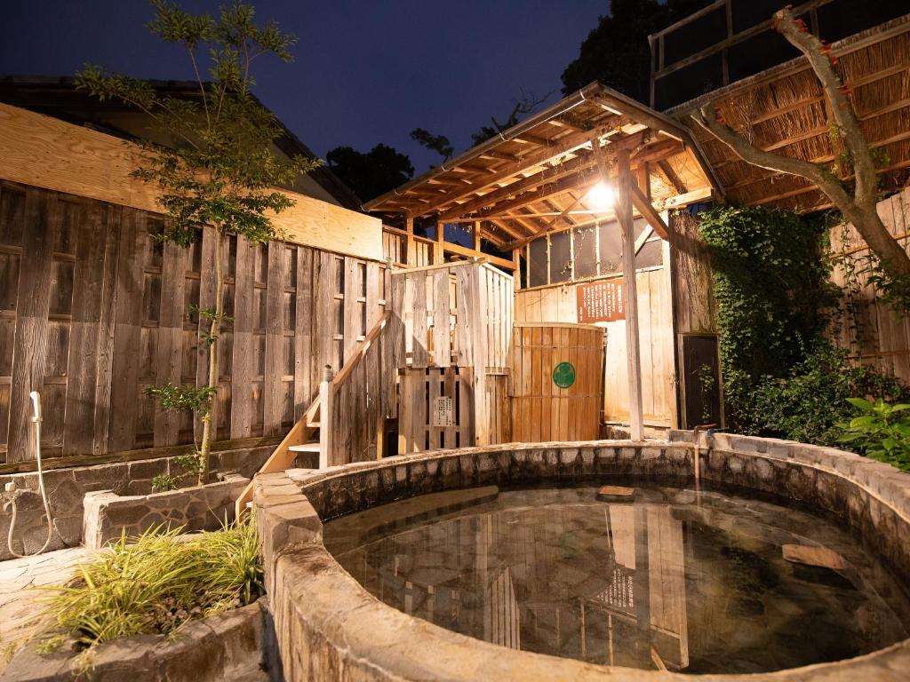 un jacuzzi dans une cour arrière avec une clôture en bois dans l'établissement HOTEL SHIRAHAMAKAN, à Shirahama