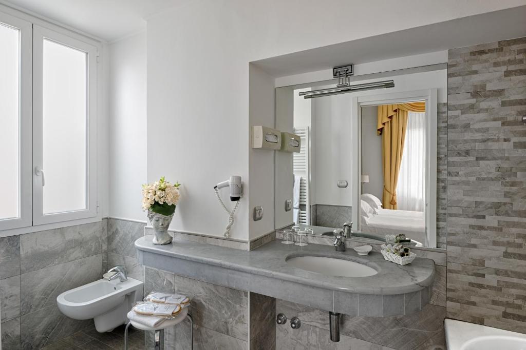 une salle de bain avec un lavabo, des toilettes et un miroir dans l'établissement Hotel Paradiso, à Sanremo