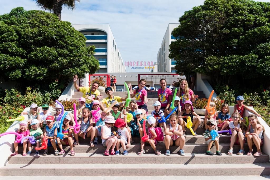 un groupe de personnes assises sur des marches avec des drapeaux dans l'établissement Aparthotel Imperial, à Bibione