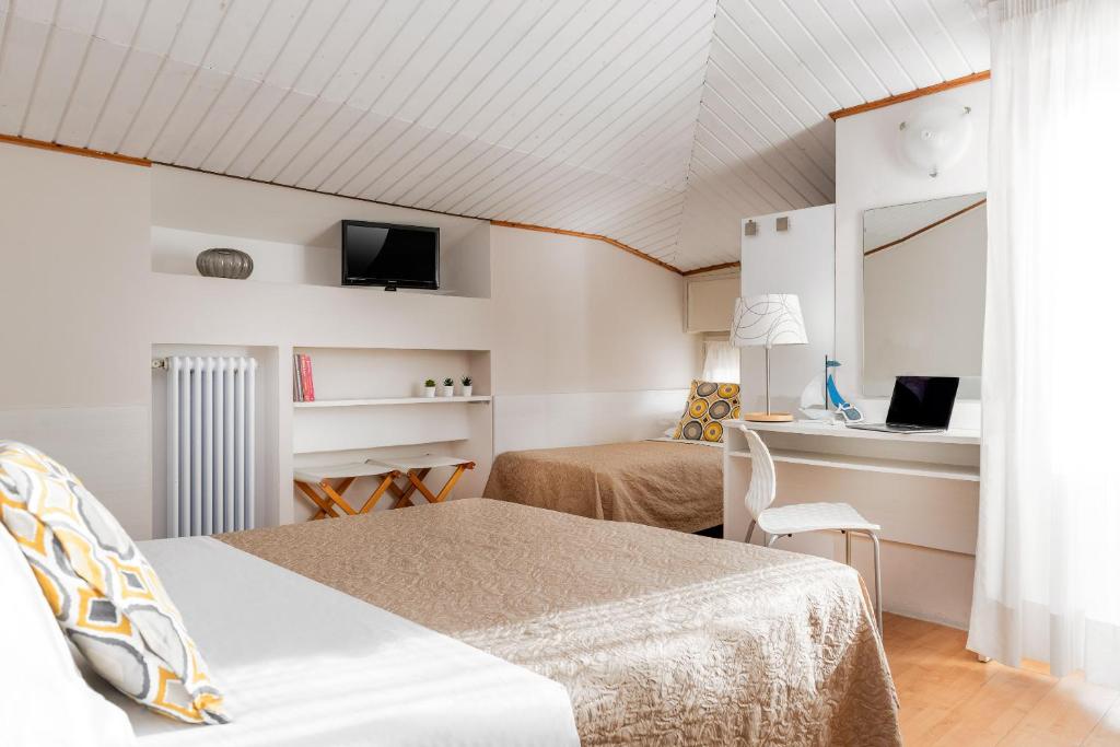 une chambre avec deux lits, un bureau et une télévision dans l'établissement Hotel Eliseo Riccione, à Riccione
