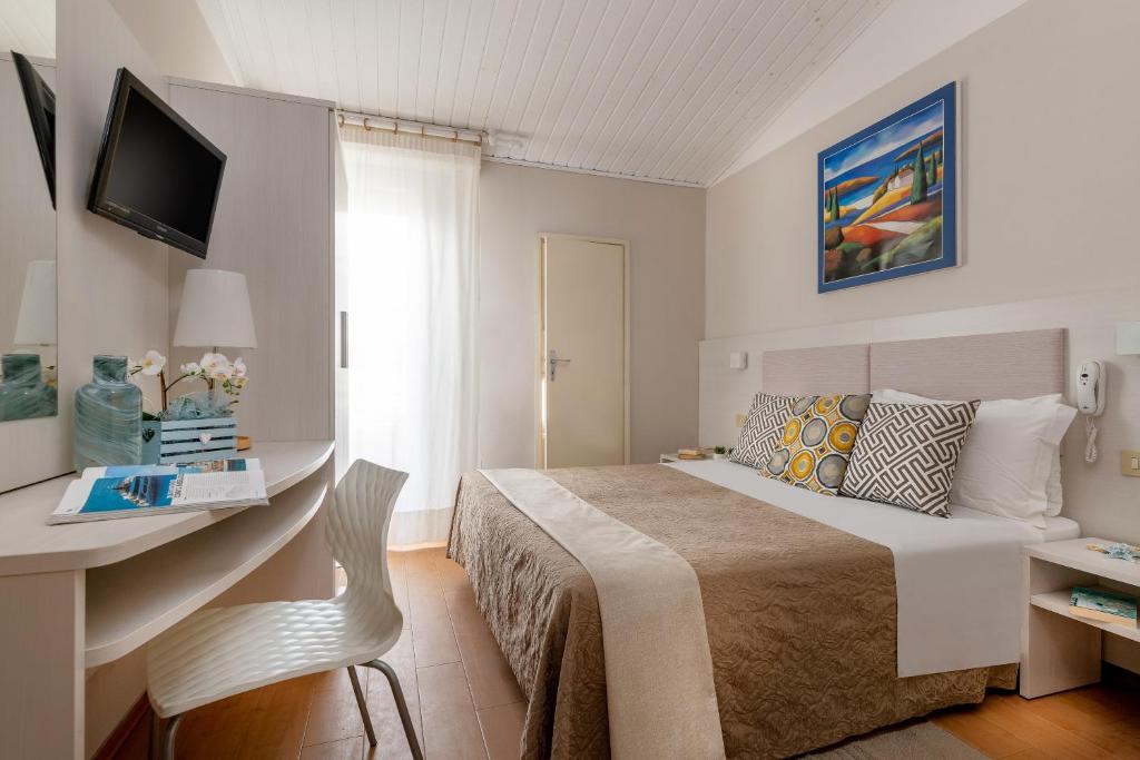 une chambre avec un lit et un bureau avec une télévision dans l'établissement Hotel Eliseo Riccione, à Riccione