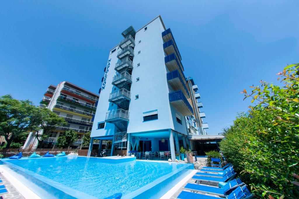 un immeuble avec une piscine devant un immeuble dans l'établissement Hotel Napoleon, à Pesaro