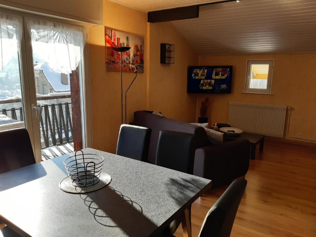 une salle à manger avec une table et des chaises et un balcon dans l'établissement Gîte Les Glycines, à Gérardmer