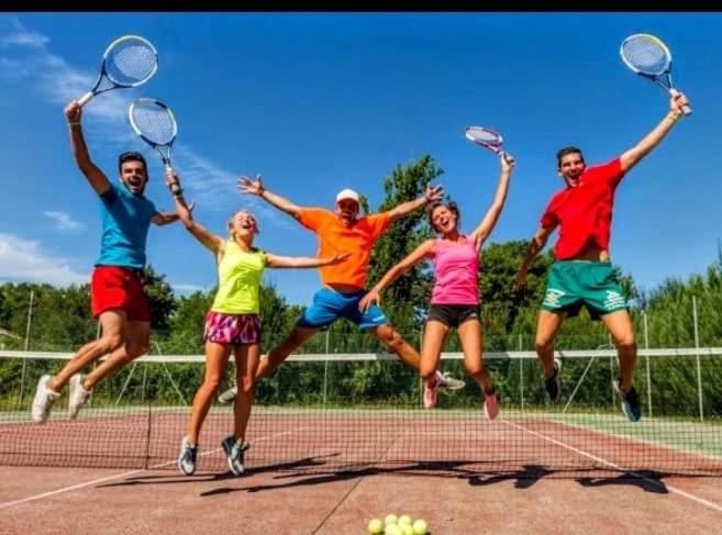 Un groupe de personnes sautant en l'air sur un court de tennis dans l'établissement Mobil-home du Lac Mimizan, à Aureilhan