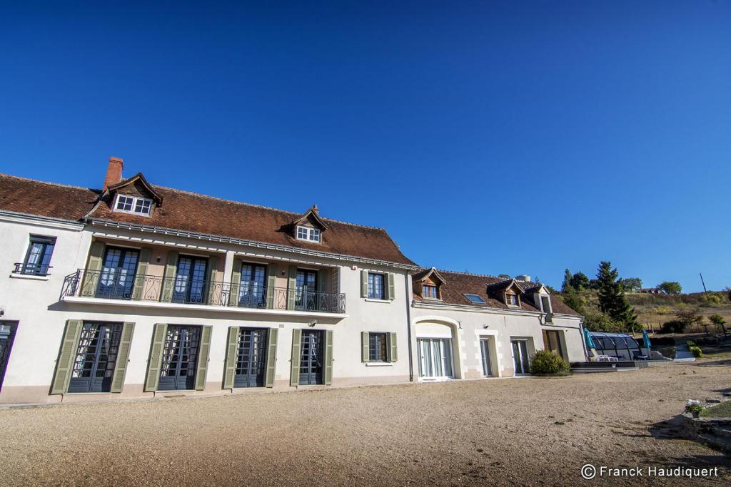 un grand bâtiment blanc avec des fenêtres donnant sur une rue dans l'établissement Gite Domaine de Trevety, à Châtillon-sur-Cher