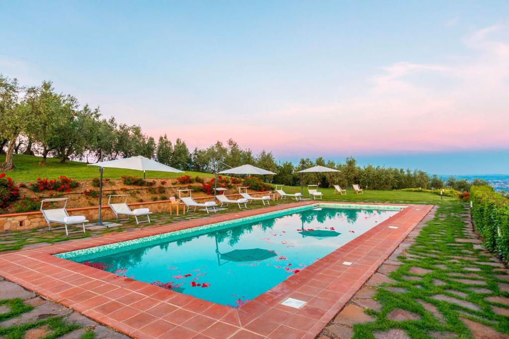 une grande piscine avec chaises et parasols dans l'établissement Villa Armonia Toscana - Homelike Villas, à Massa e Cozzile