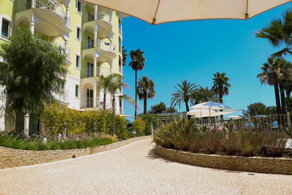 une passerelle menant à un hôtel avec des palmiers dans l'établissement Smeraldo Suites & Spa, à San Benedetto del Tronto