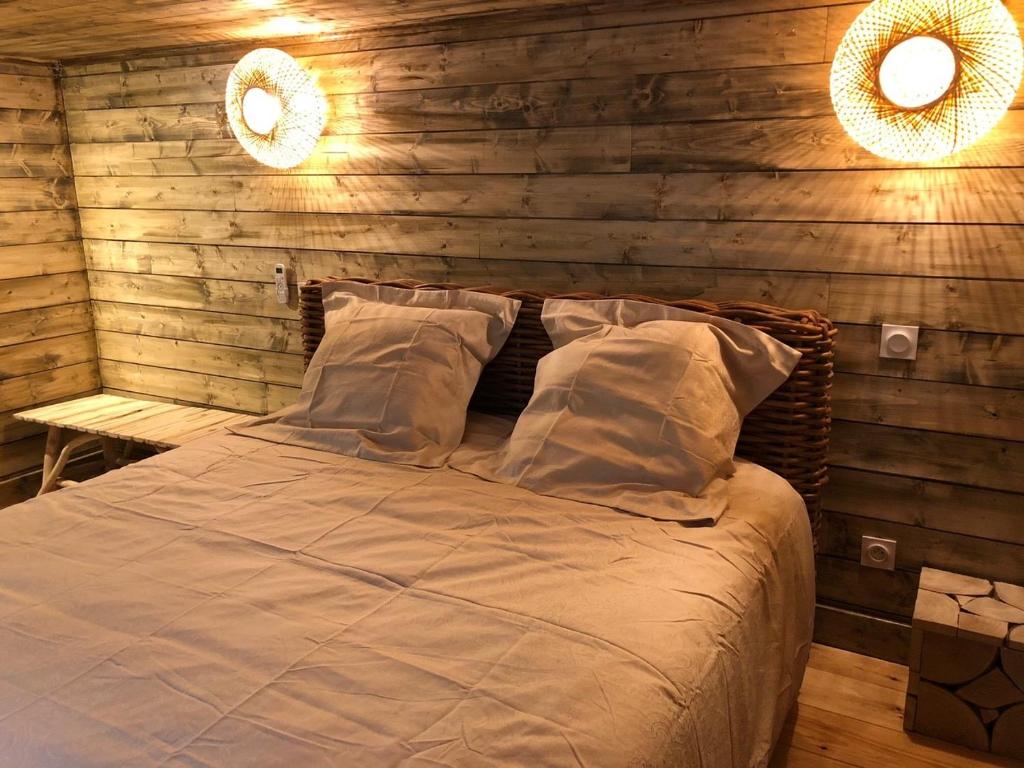 un lit dans une chambre avec un mur en bois dans l'établissement Les Crouquets La cabane SPA des Noyers, à Jayac
