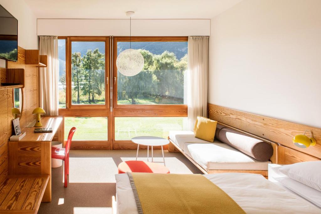 une chambre avec un lit, un canapé et une fenêtre dans l'établissement Seehotel Ambach, à Caldaro