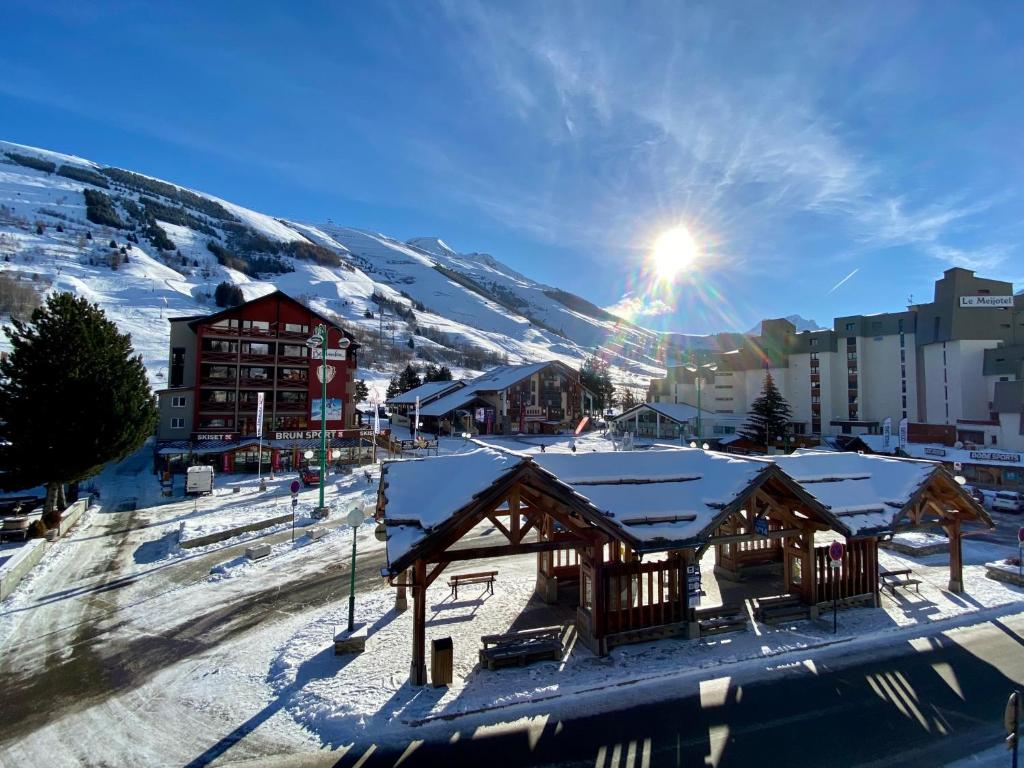 une station de ski avec des bâtiments recouverts de neige et le soleil dans l'établissement L'Écrin Alpin - somptueux 4 pièces NEUF cœur station, à Les Deux Alpes