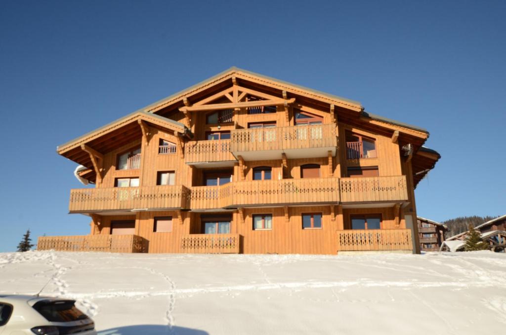 un bâtiment en bois au sommet d'une pente enneigée dans l'établissement Chalet A, Village des Lapons Les Saisies, 3 chambres et 1 espace nuit mezzanine, aux Saisies