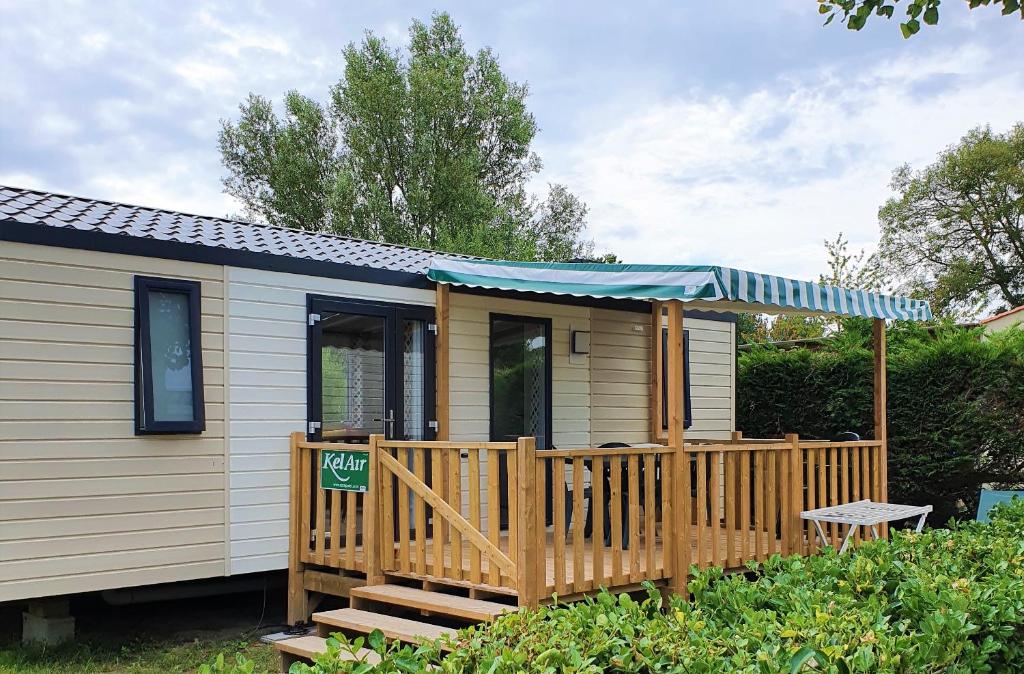 une petite maison avec une terrasse et un auvent bleu dans l'établissement Mobile Homes by KelAir at Camping La Yole, à Saint-Jean-de-Monts