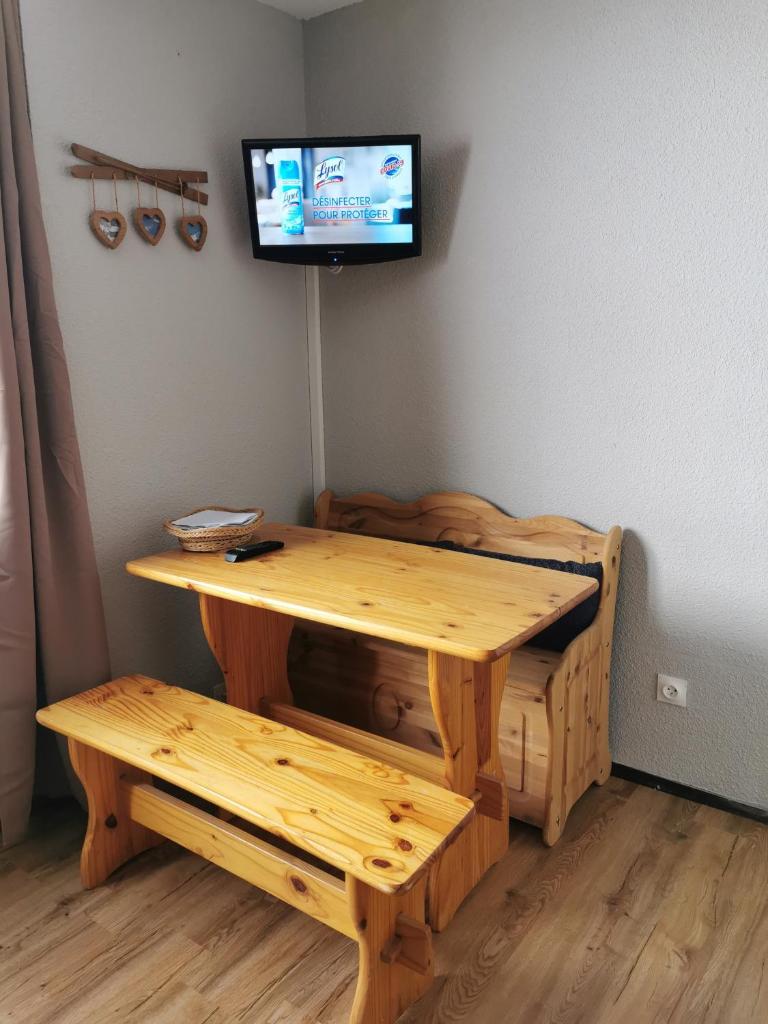 une table et un banc en bois avec une télévision murale dans l'établissement Studio rénové Chamrousse, au pied des pistes., à Chamrousse 7 autres photos