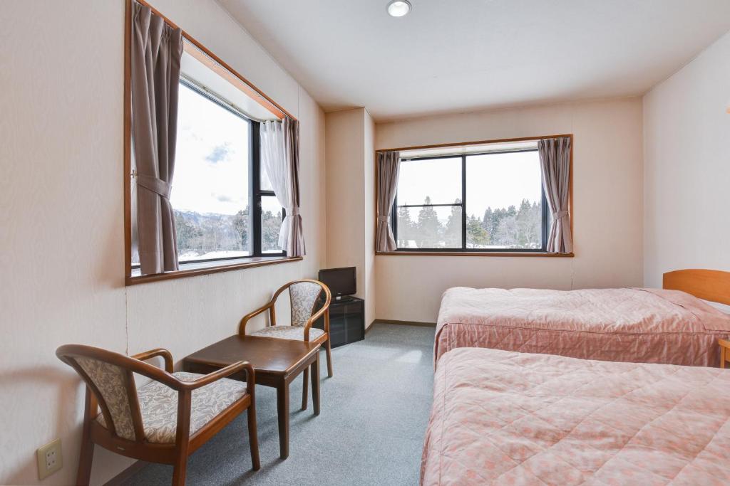 Cette chambre comprend deux lits, une chaise et deux fenêtres. dans l'établissement Kanoe, à Iiyama 37 autres photos