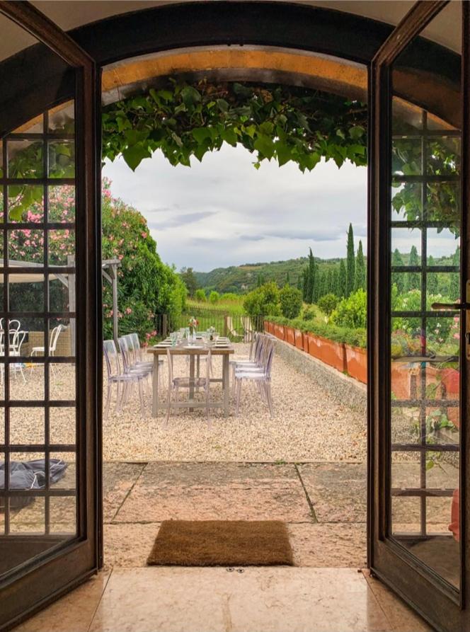 Une porte ouverte s'ouvre sur une terrasse avec une table et des chaises. dans l'établissement Villa Avesa, à Vérone