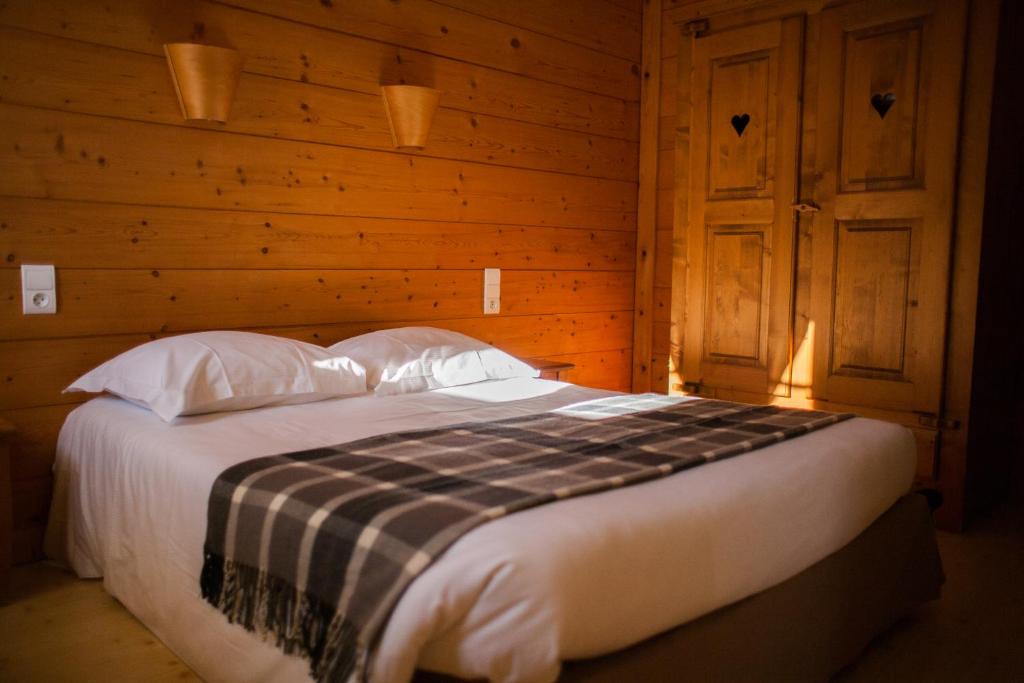 un lit dans une chambre avec un mur en bois dans l'établissement LOGIS Les Arobiers, à Lamoura