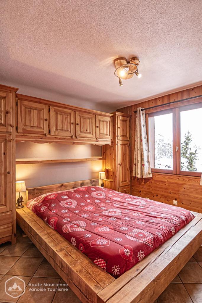 une chambre avec un grand lit avec une couette rouge dans l'établissement La Soldanelle, à Lanslevillard