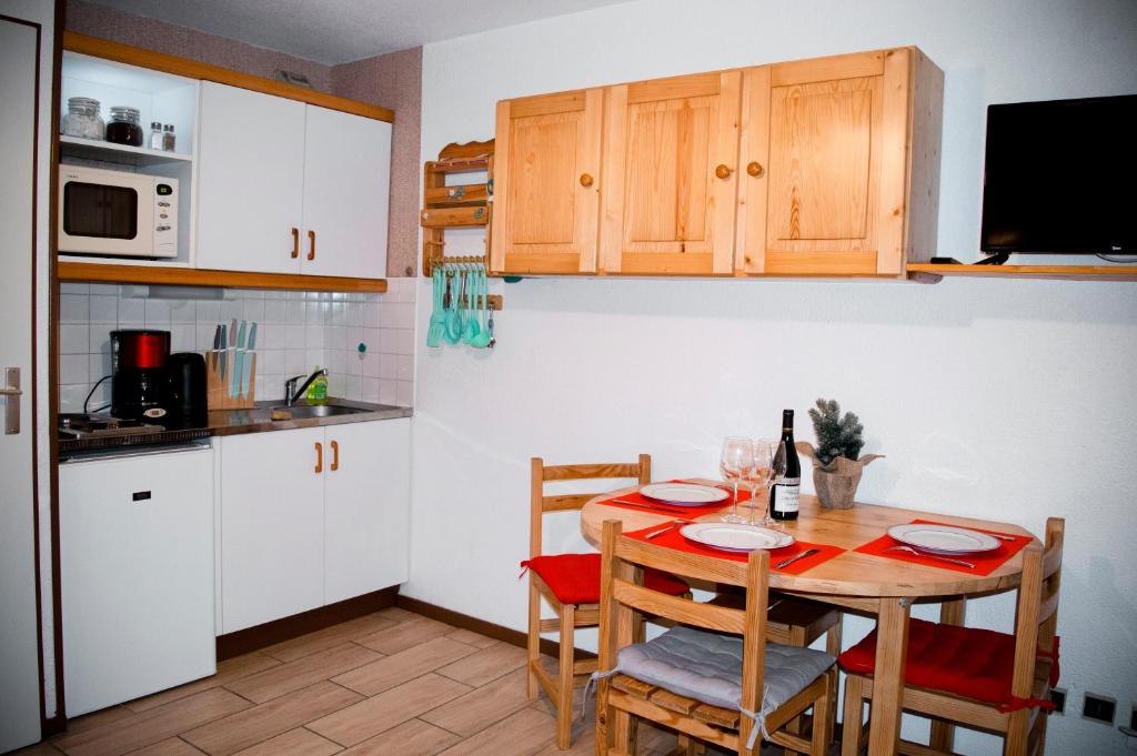 une cuisine avec une table et des placards blancs dans l'établissement Your apartment near the ski lift, à Aime La Plagne