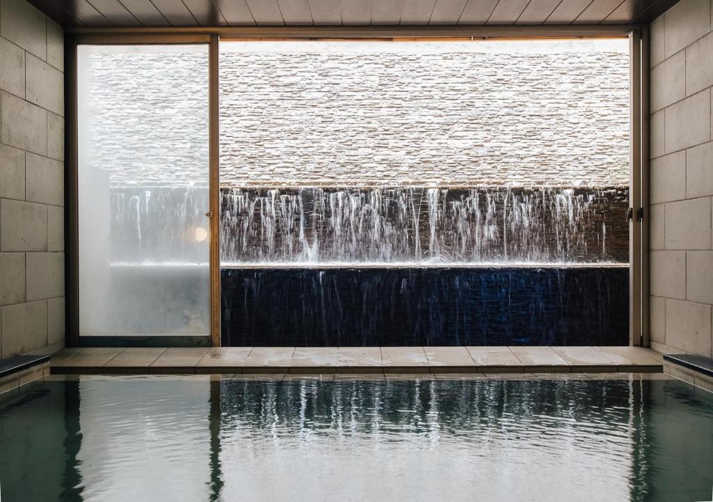 - une cascade dans un bâtiment avec piscine d'eau dans l'établissement Atami Fuga, à Atami