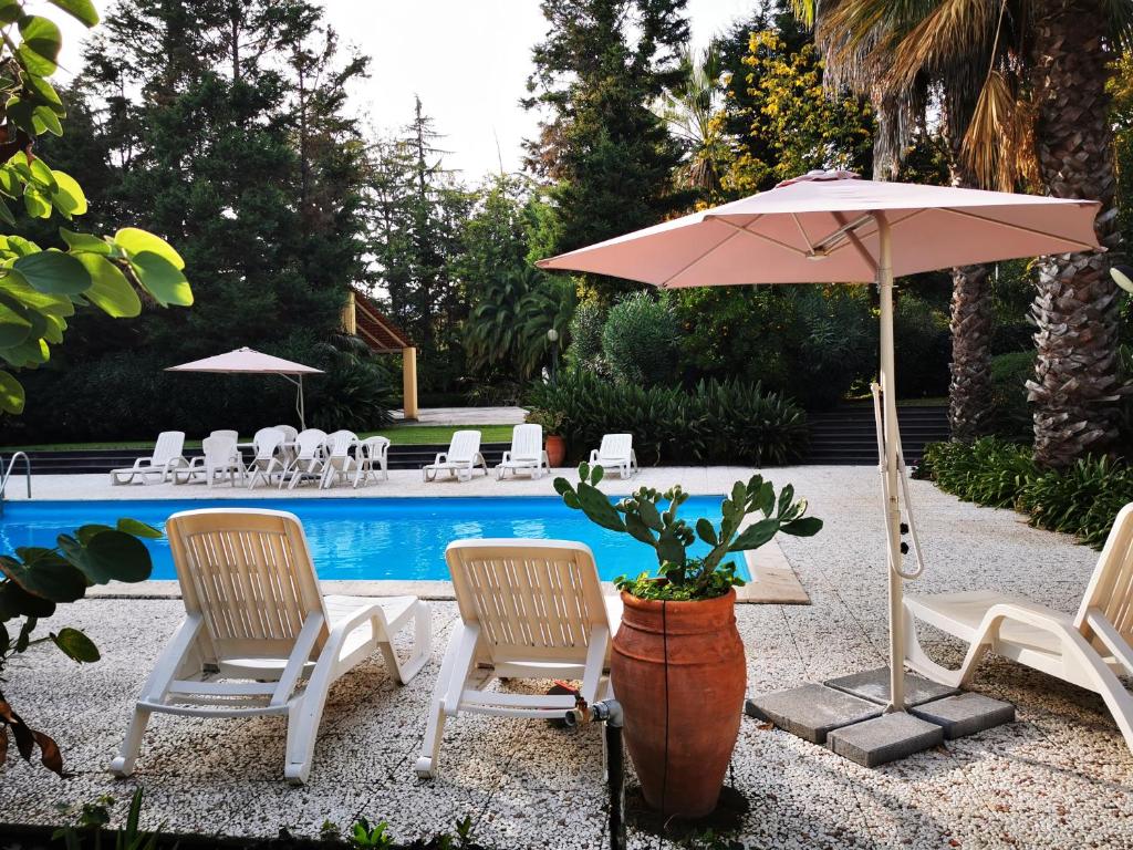 une terrasse avec des chaises et un parasol ainsi qu'une piscine dans l'établissement Villa Solaria, à Santa Venerina