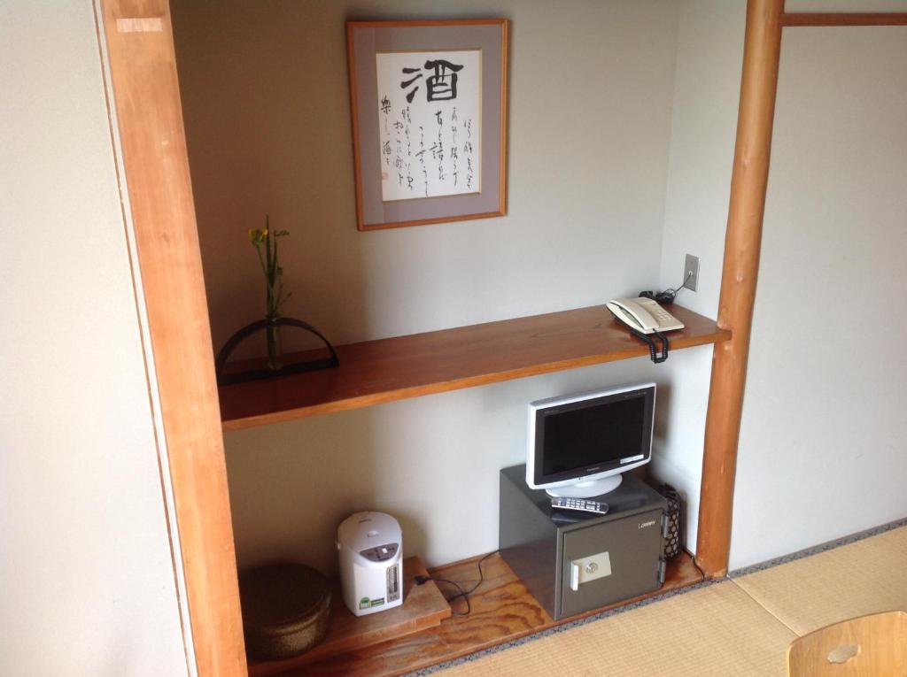 Cette chambre dispose d'un bureau et d'un ordinateur sur une étagère. dans l'établissement Yamaichi Bekkan, à Miyajima