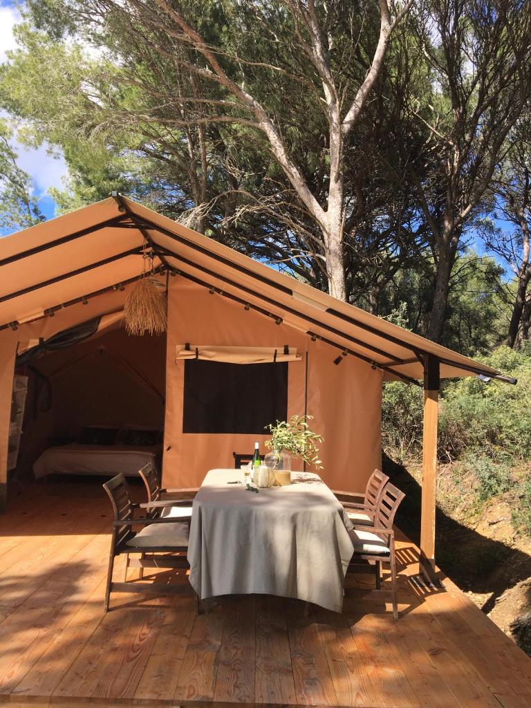 une tente avec une table et des chaises sur une terrasse dans l'établissement Saint Paul le Marseillais Tentes Equippees Hébergements Insolites Lodges, à Mèze 17 autres photos