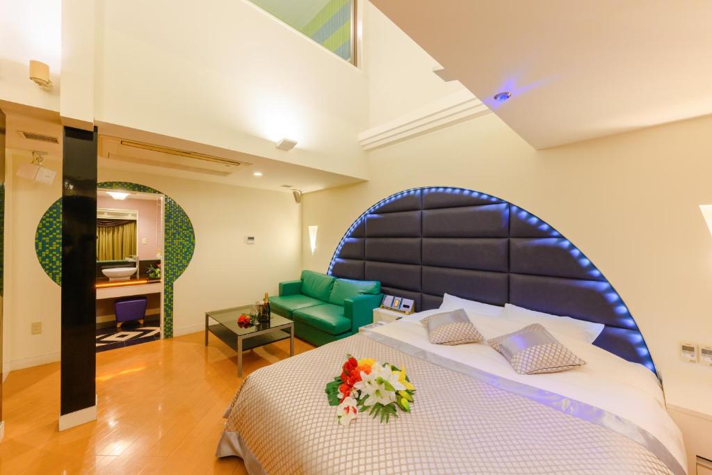 - une chambre avec un grand lit et un canapé vert dans l'établissement HOTEL MYTH-J -ホテル マイス ジェイ- adult only, à Sakaide