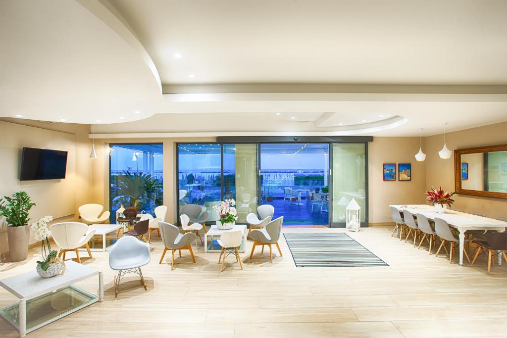 une grande pièce avec des tables, des chaises et des fenêtres dans l'établissement Hotel Agostini, à Bellaria-Igea Marina